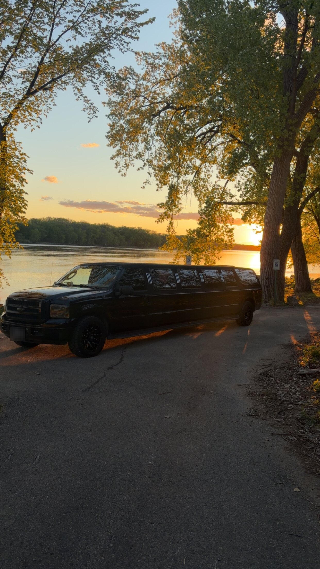 Black stretch limo parked by the river at sunset