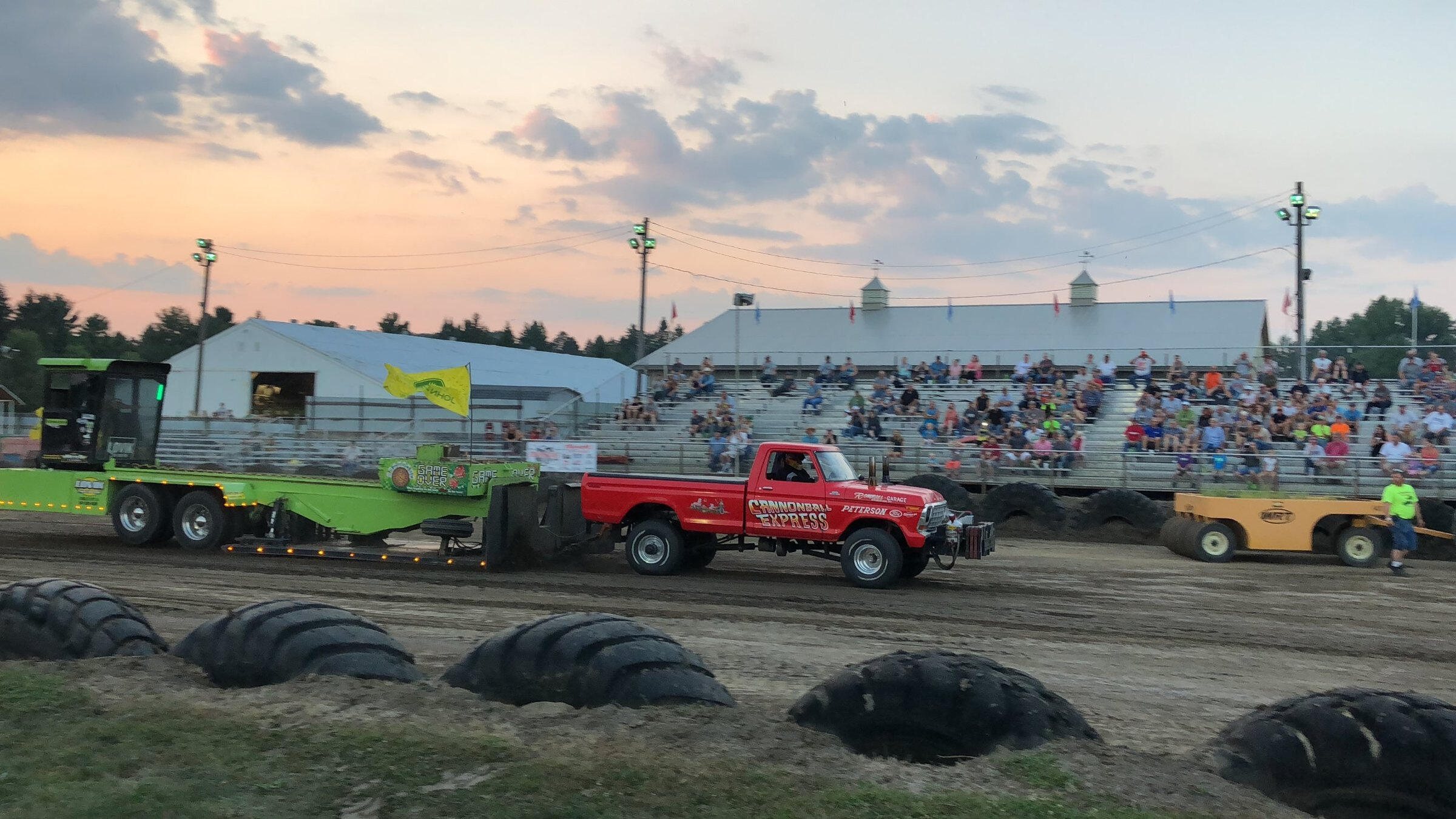 Red pulling truck competing at a truck pull at dusk